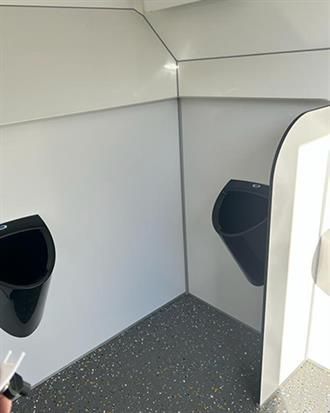 Ein Badezimmer mit zwei Urinalen und einem Spiegel.