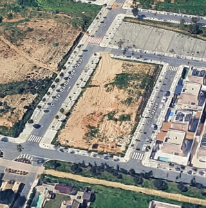 Vista aérea de una plaza de la ciudad con un edificio con techo blanco rodeado de edificios con techos de terracota.