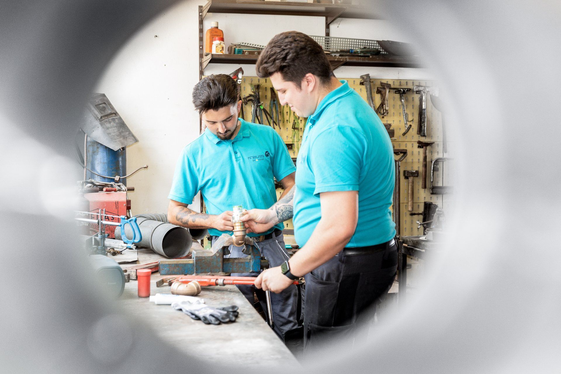 Zwei Männer arbeiten in einer Werkstatt an einem Rohr.