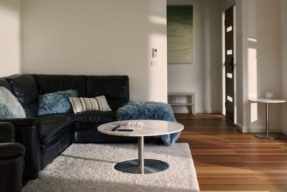 Modern living room with black sectional sofa, round coffee table, and sunlit wooden floor