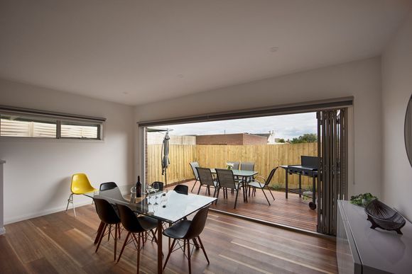 Modern dining room opens to a deck with outdoor seating and a fenced backyard