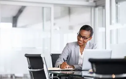 A woman is sitting at a table in front of a laptop computer.