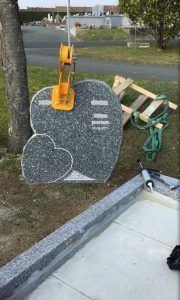 Tombe en granit avec stèle en cours de scellement