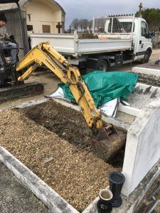 Pelleteuse en train de creuser une fosse dans le cimetière