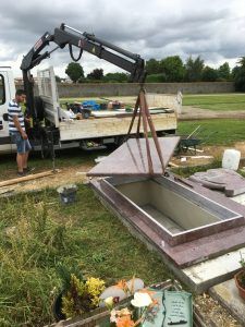 Camion plateau déchargeant le couvercle d'une tombe