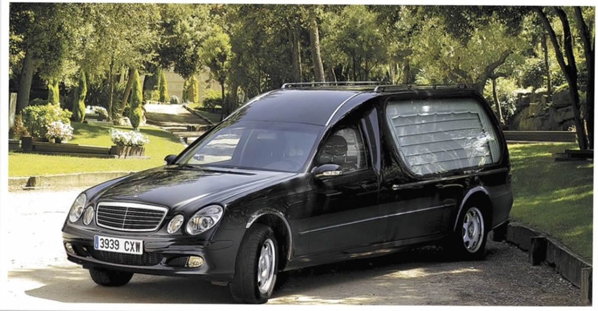 Un coche fúnebre negro está estacionado al costado de la carretera.