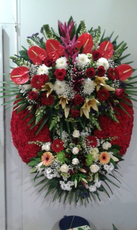 Una gran corona de flores rojas y blancas cuelga en una pared.