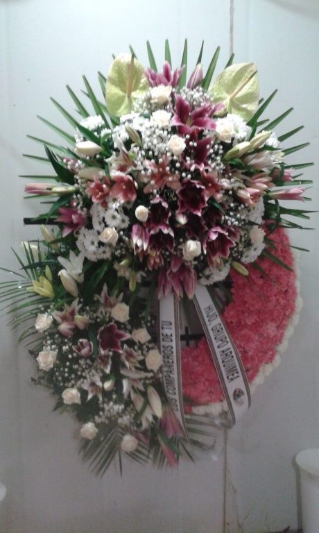 Una gran corona de flores reposa sobre una pared blanca.