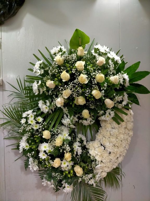 Una corona de flores blancas cuelga en una pared.