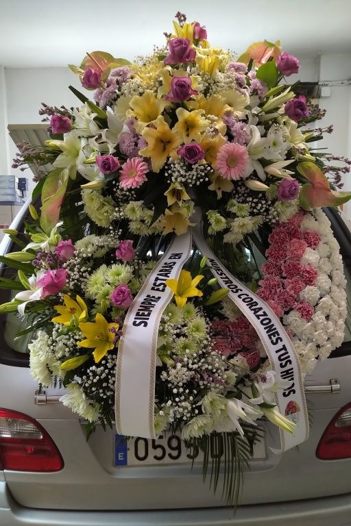 Una gran corona de flores está en la parte trasera de un coche.