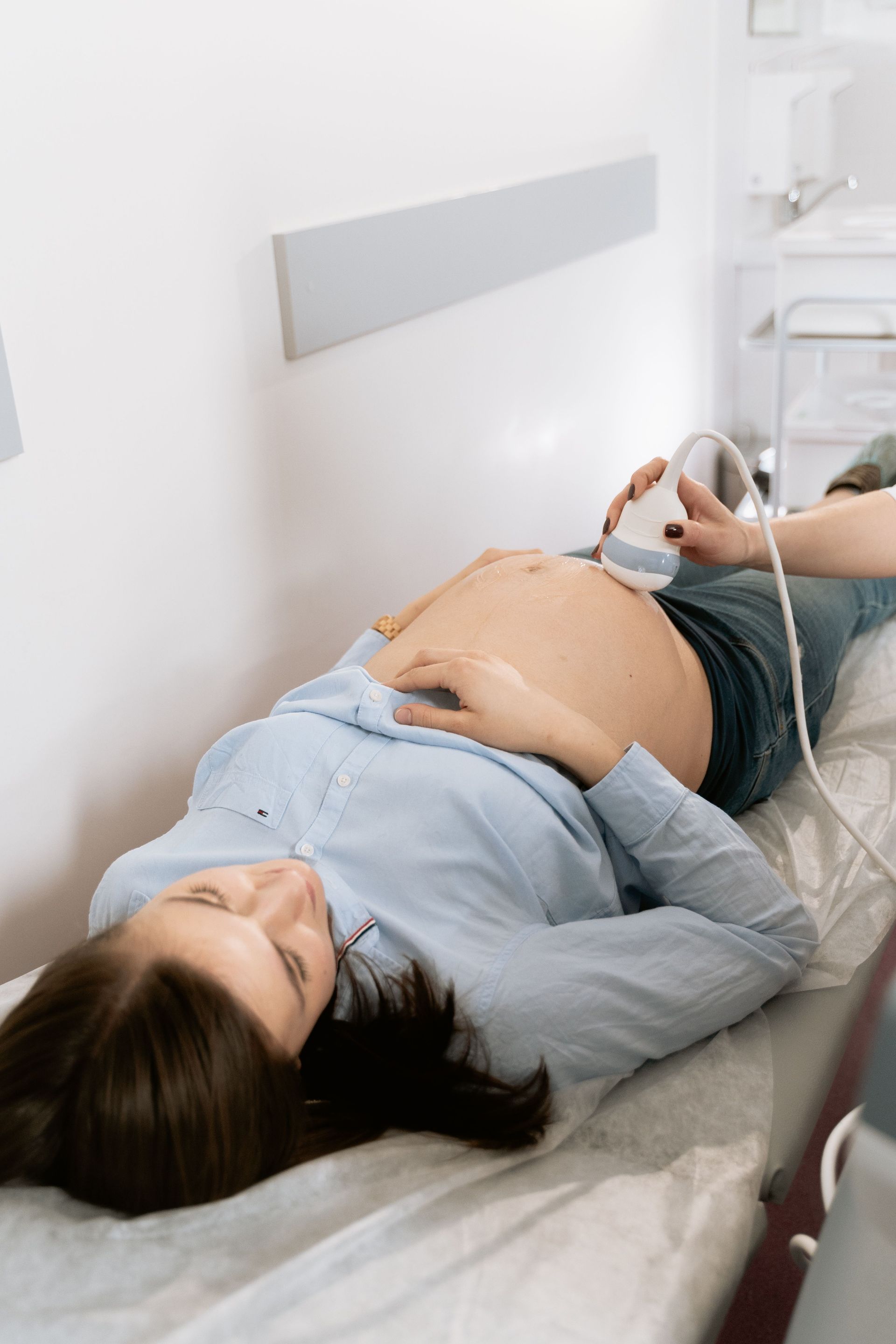 La patiente est allongée sur un lit médical pendant qu'une échographie abdominale est réalisée.