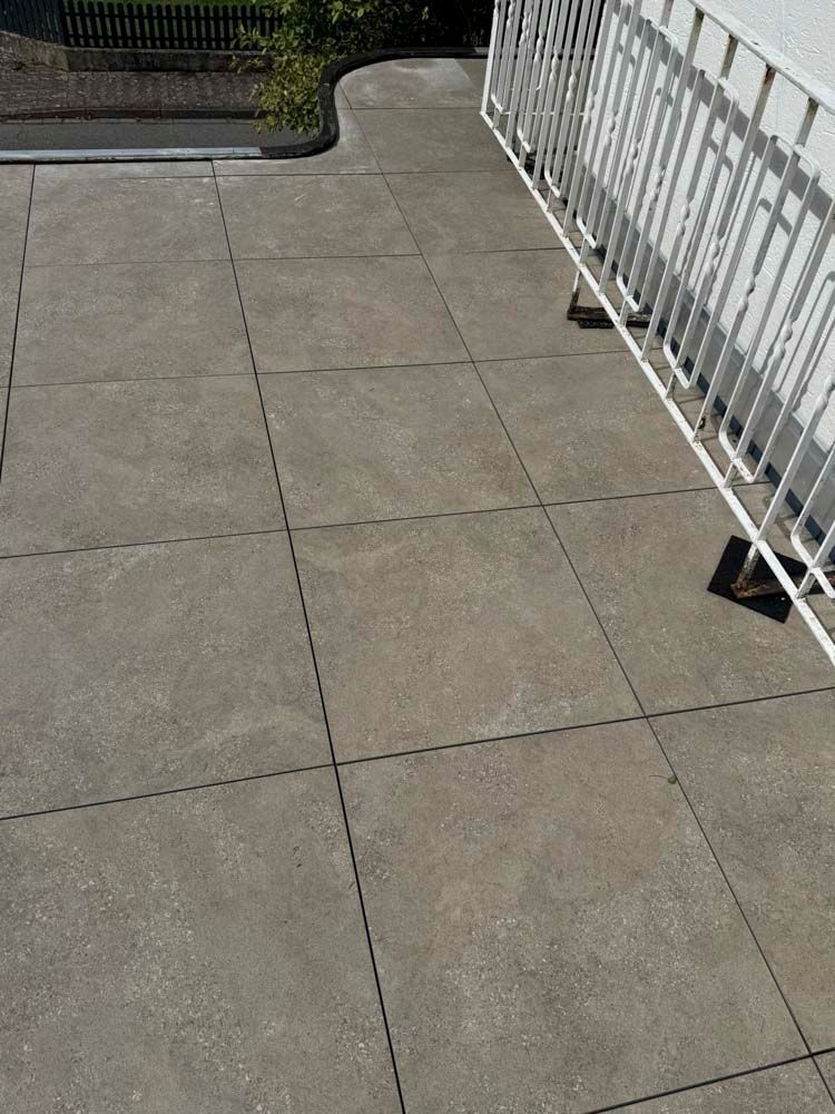 Betonterrasse mit quadratischem Muster und weißem Geländer.