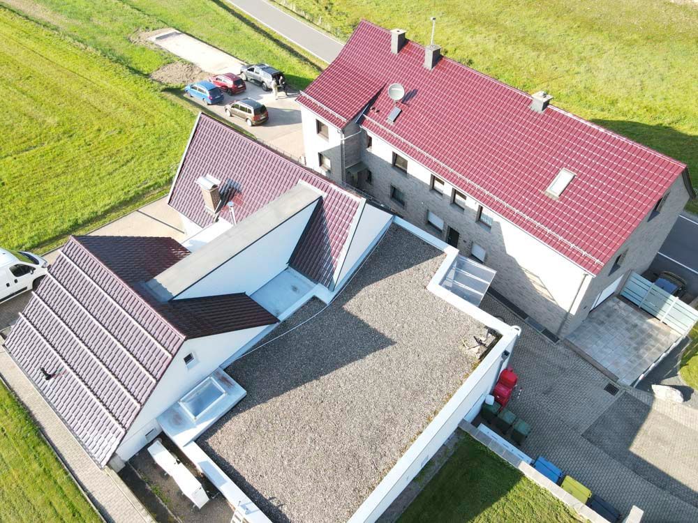 Luftaufnahme von Gebäuden mit roten und braunen Dächern, umgeben von grünen Feldern.