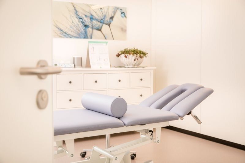 Ein Raum mit einem Behandlungstisch und einer Kommode. Foto von der Physiotherapie Giger GmbH