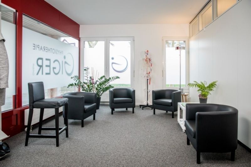 Ein Wartezimmer mit schwarzen Stühlen und einer Pflanze. Foto von der Physiotherapie Giger GmbH