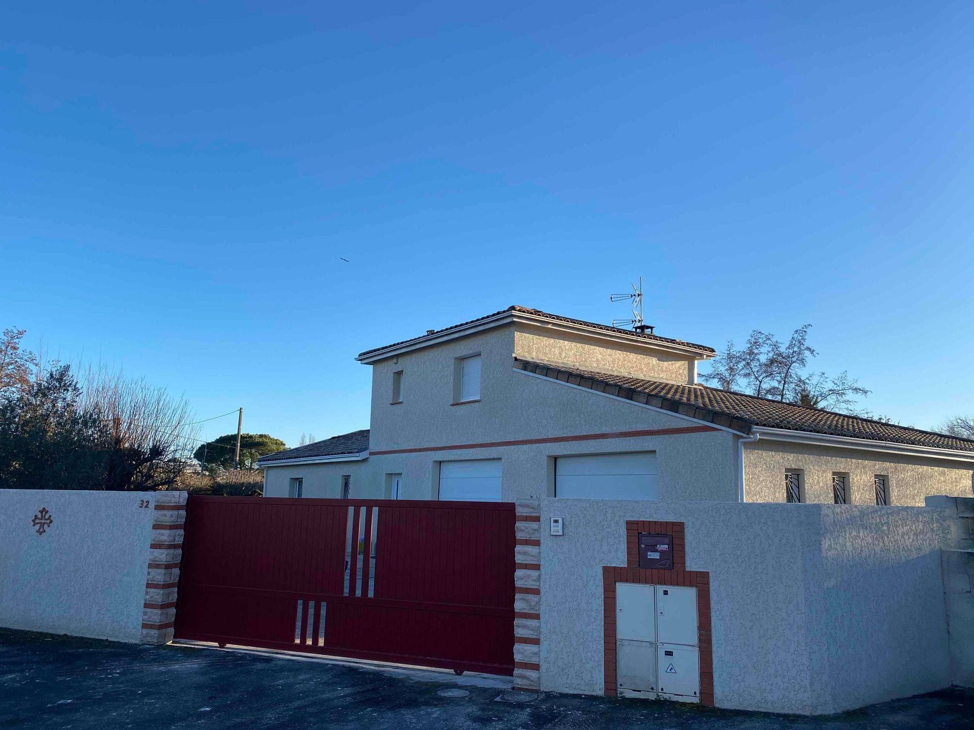 Maison blanche avec portail et pancarte de l'entreprise lors de travaux de façade