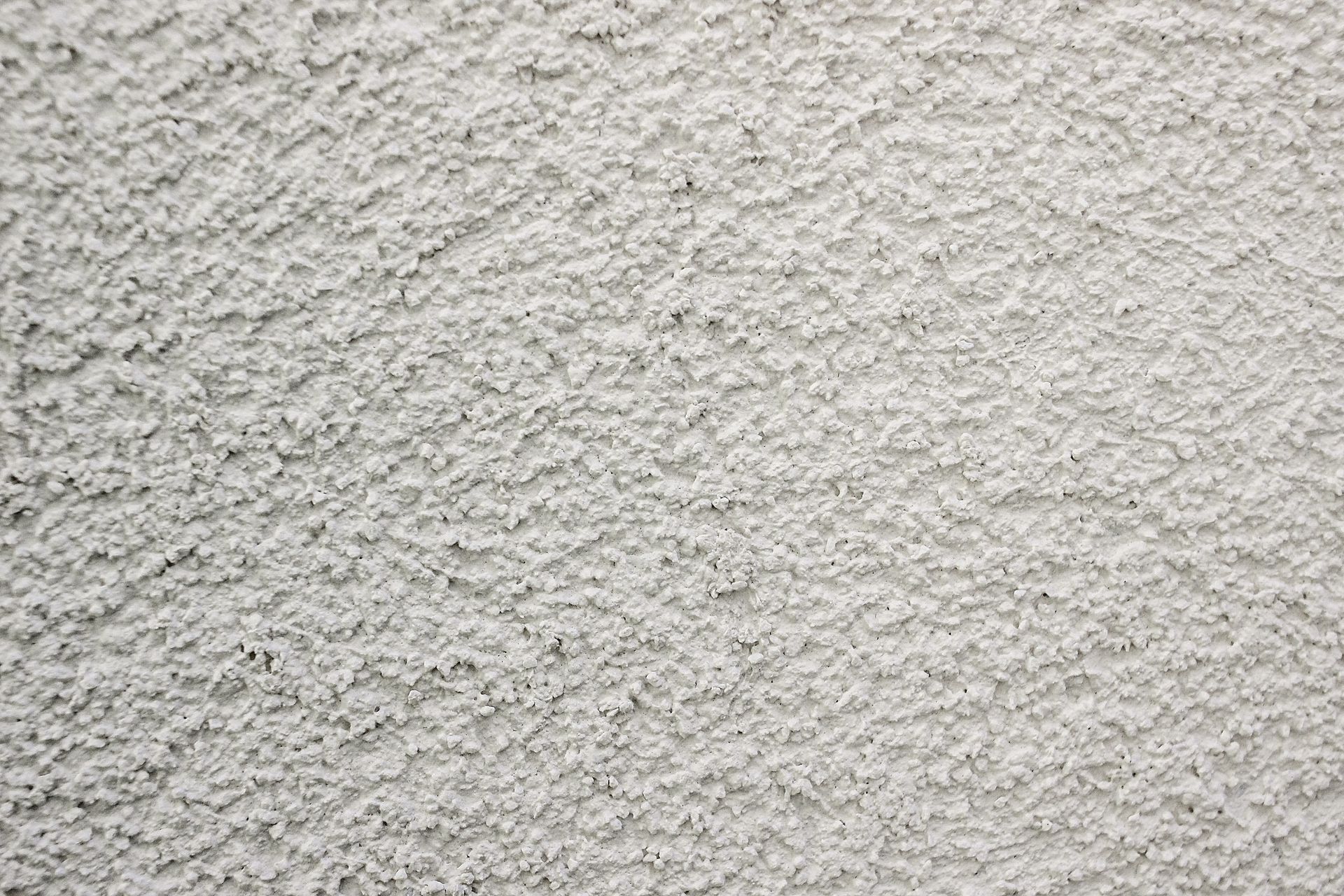 Gros plan sur un mur gris clair à la surface rugueuse et texturée