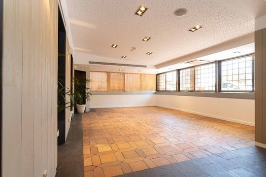 Una gran habitación vacía con piso de ladrillo y muchas ventanas.