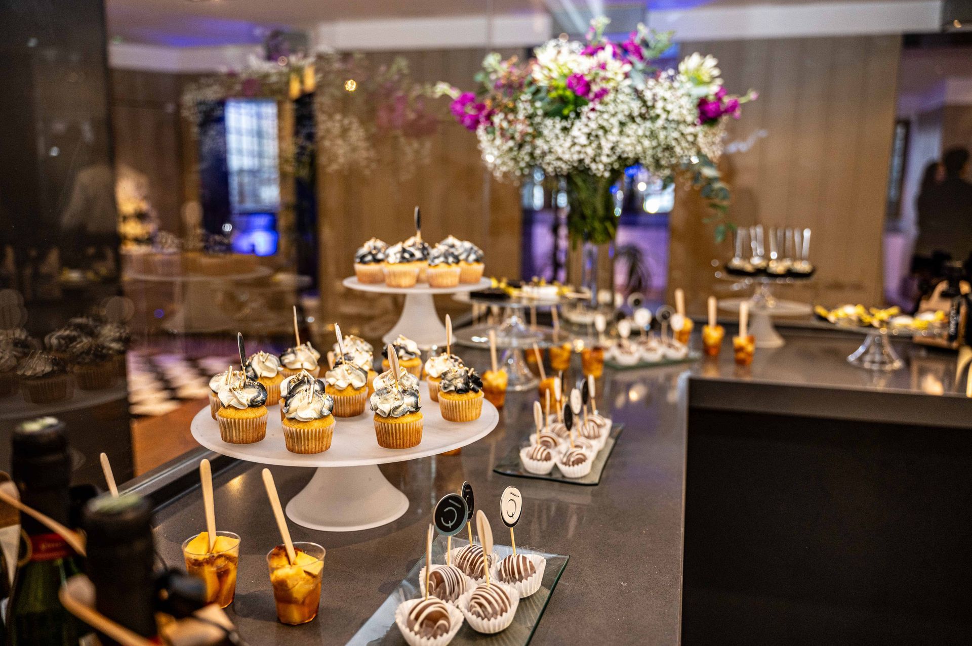Una mesa cubierta con cupcakes y un jarrón con flores.