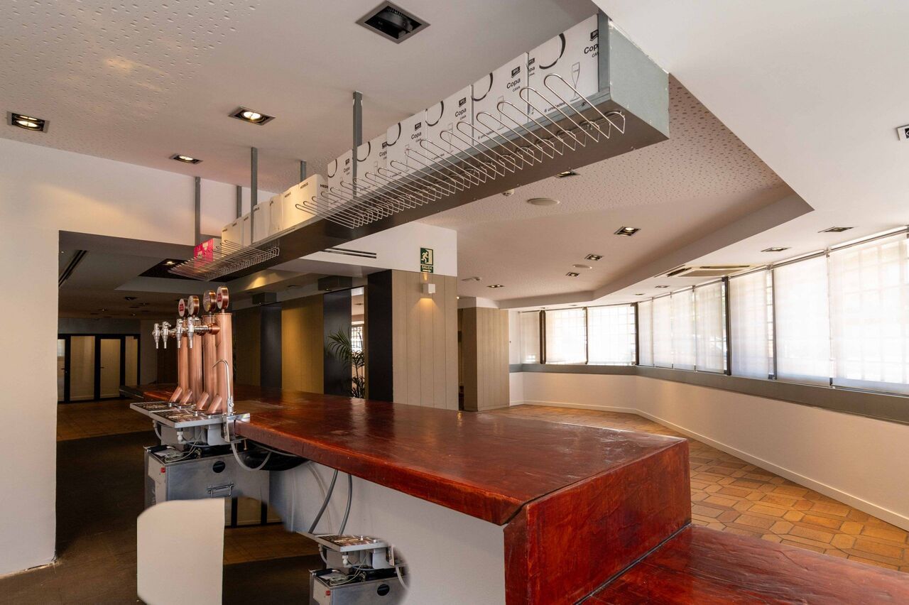 Una gran sala vacía con un bar y muchas ventanas.