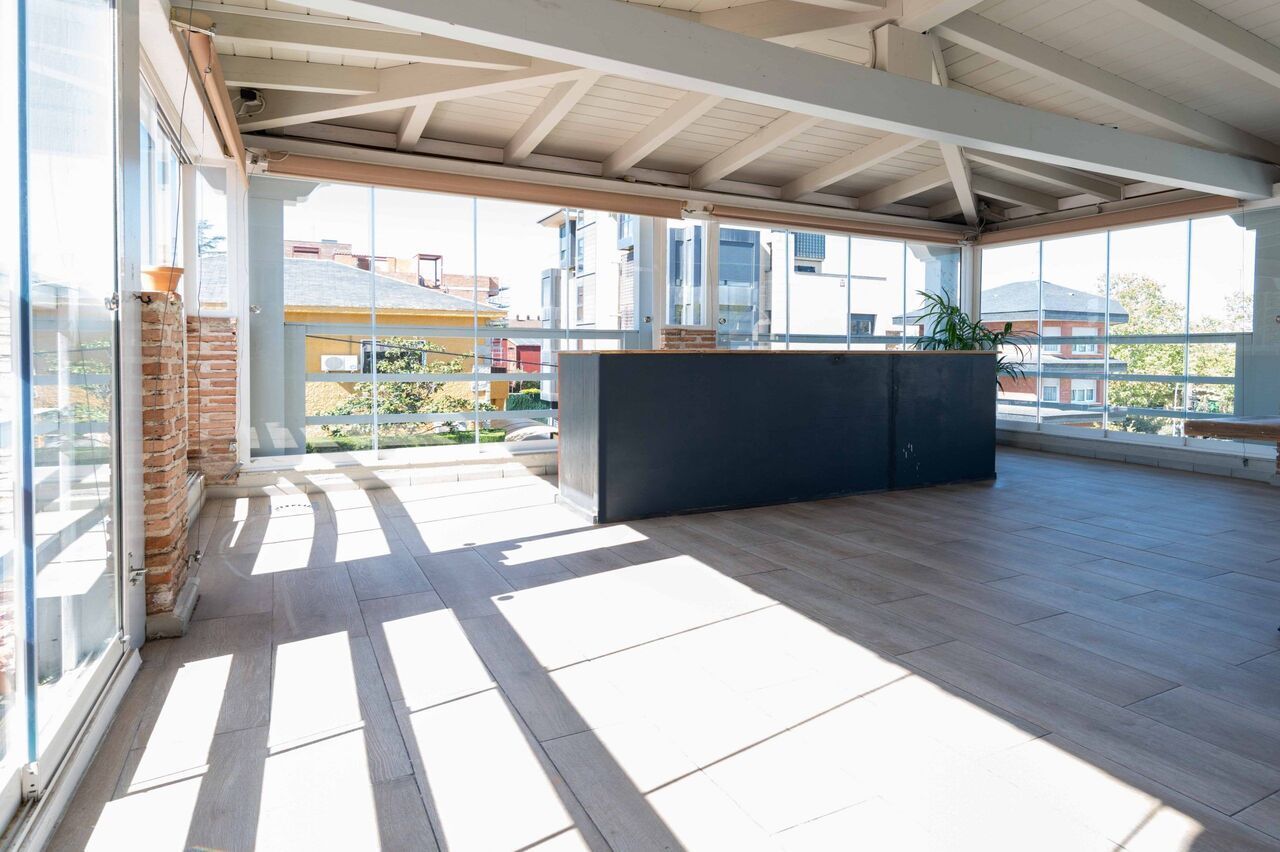 Una habitación grande con muchas ventanas y suelo de madera.