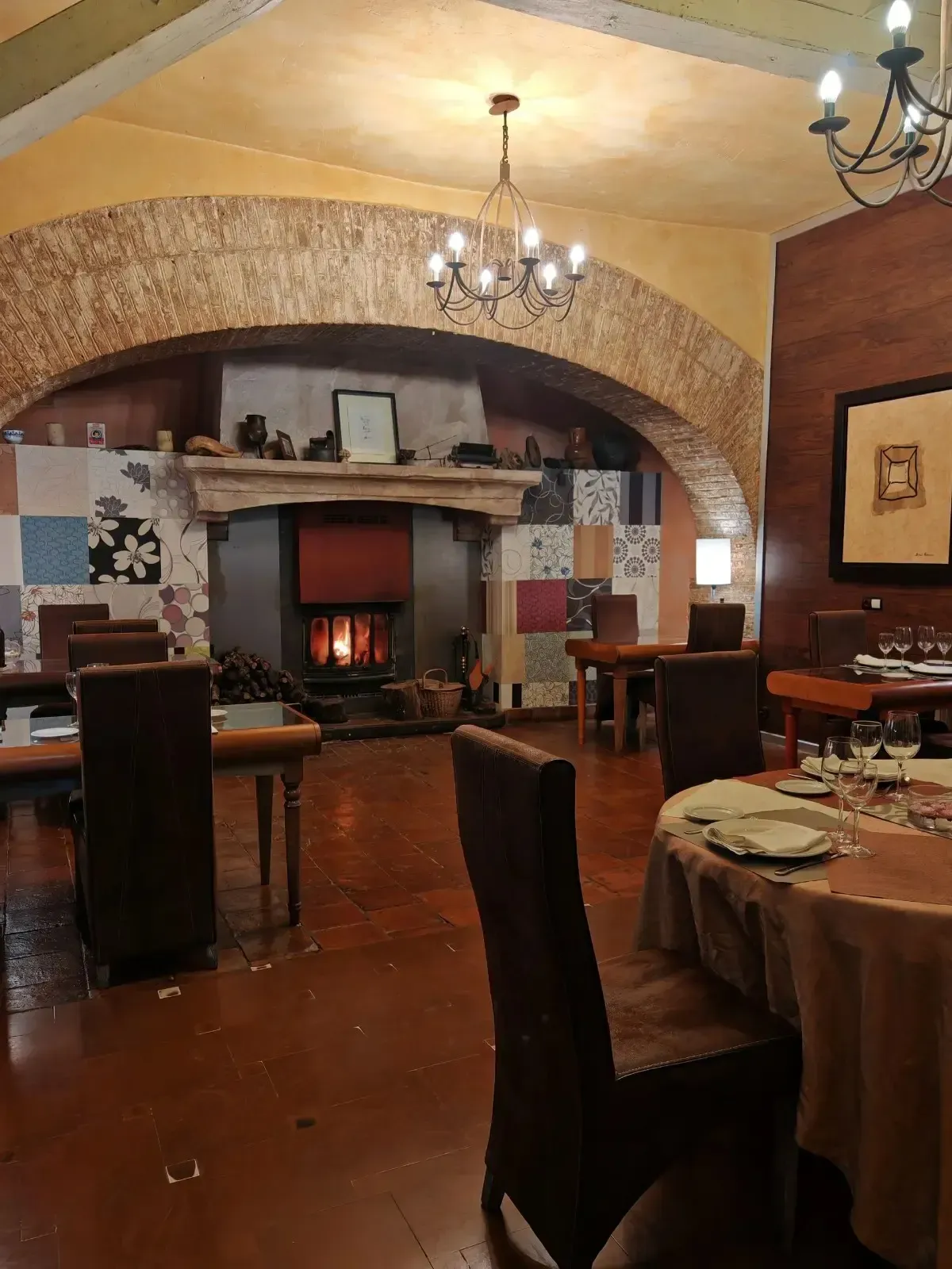 Comedor con mesa redonda preparada para invitados, sillas blancas, arte de pared colorido y entrada arqueada.