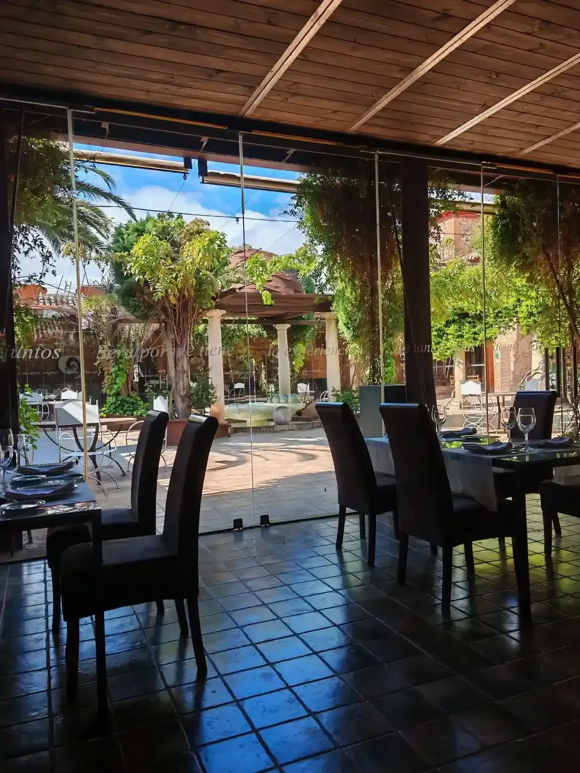 Comedor con mesa redonda preparada para invitados, sillas blancas, arte de pared colorido y entrada arqueada.