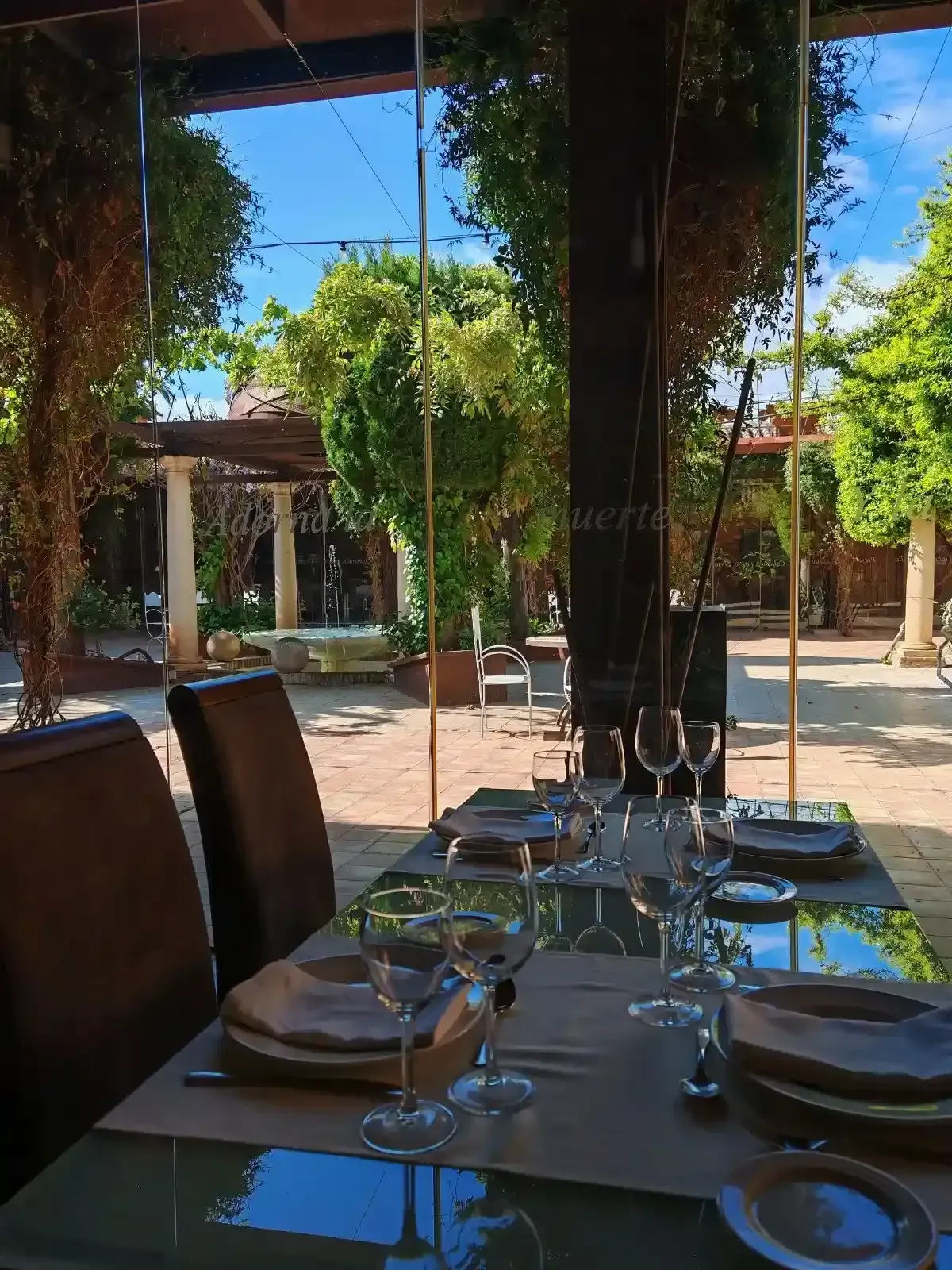 Comedor con mesa redonda preparada para invitados, sillas blancas, arte de pared colorido y entrada arqueada.