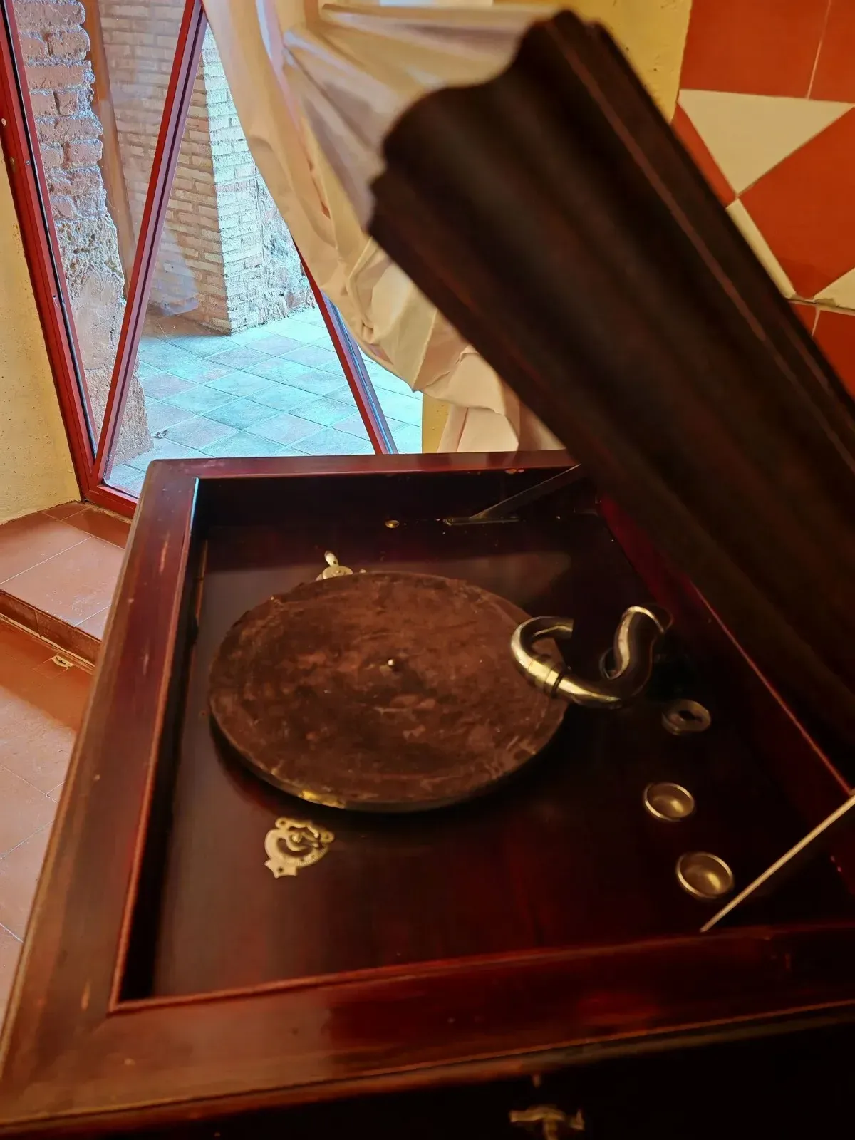 Comedor con mesa redonda preparada para invitados, sillas blancas, arte de pared colorido y entrada arqueada.