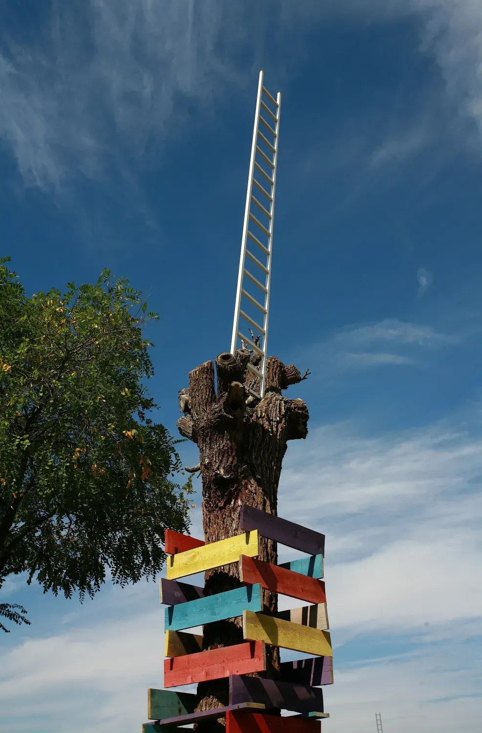 Estructura de madera colorida con escalera que llega hasta el cielo azul.