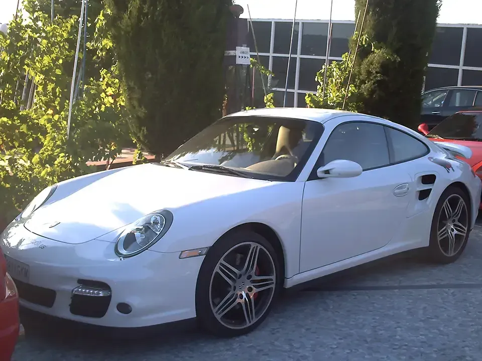 Coche deportivo Porsche de color blanco aparcado en el exterior.
