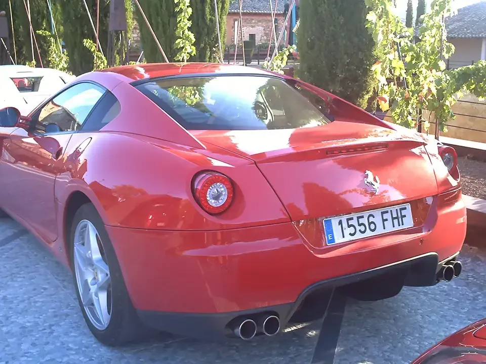 Ferrari cupé rojo aparcado en el exterior con matrícula española.