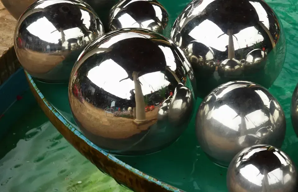 Esferas de metal brillantes flotando en agua verde.