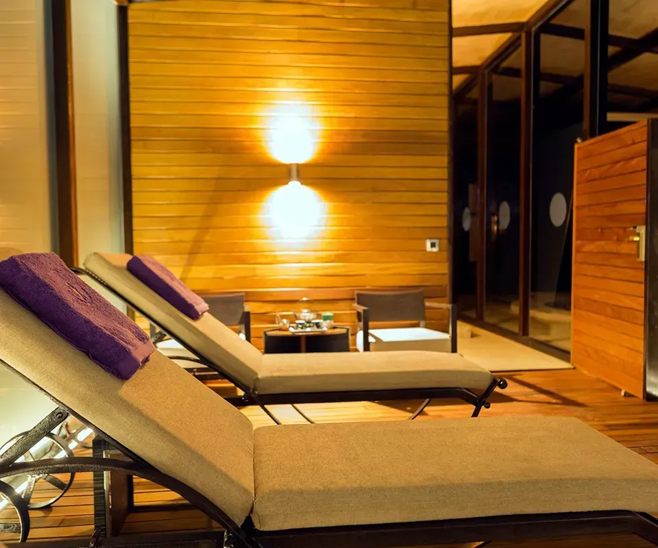 Salón spa con dos tumbonas y pared de madera.