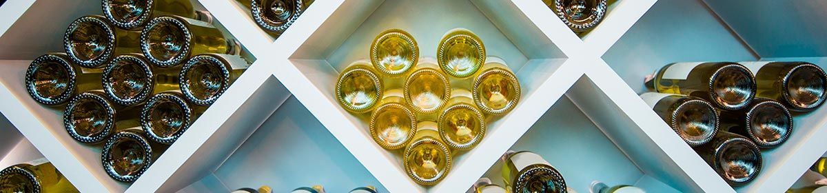 Botellas de vino almacenadas en un botellero de madera blanca.