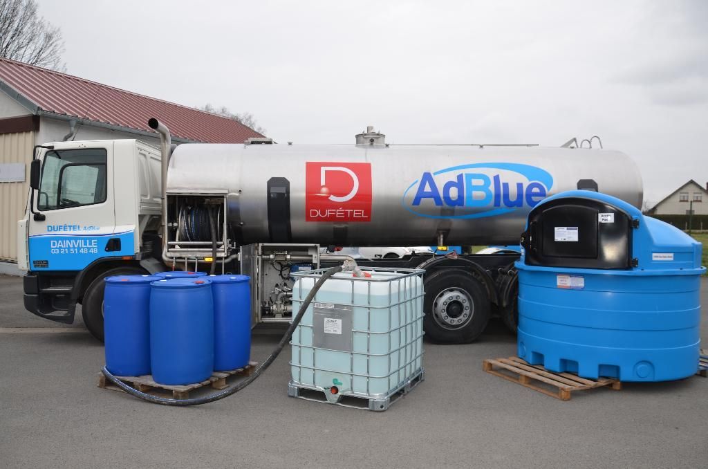 Camion-citerne bleu avec des barils et des conteneurs dans une zone industrielle