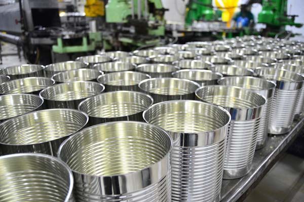 Des rangées de boîtes métalliques brillantes sur un convoyeur industriel dans une usine.