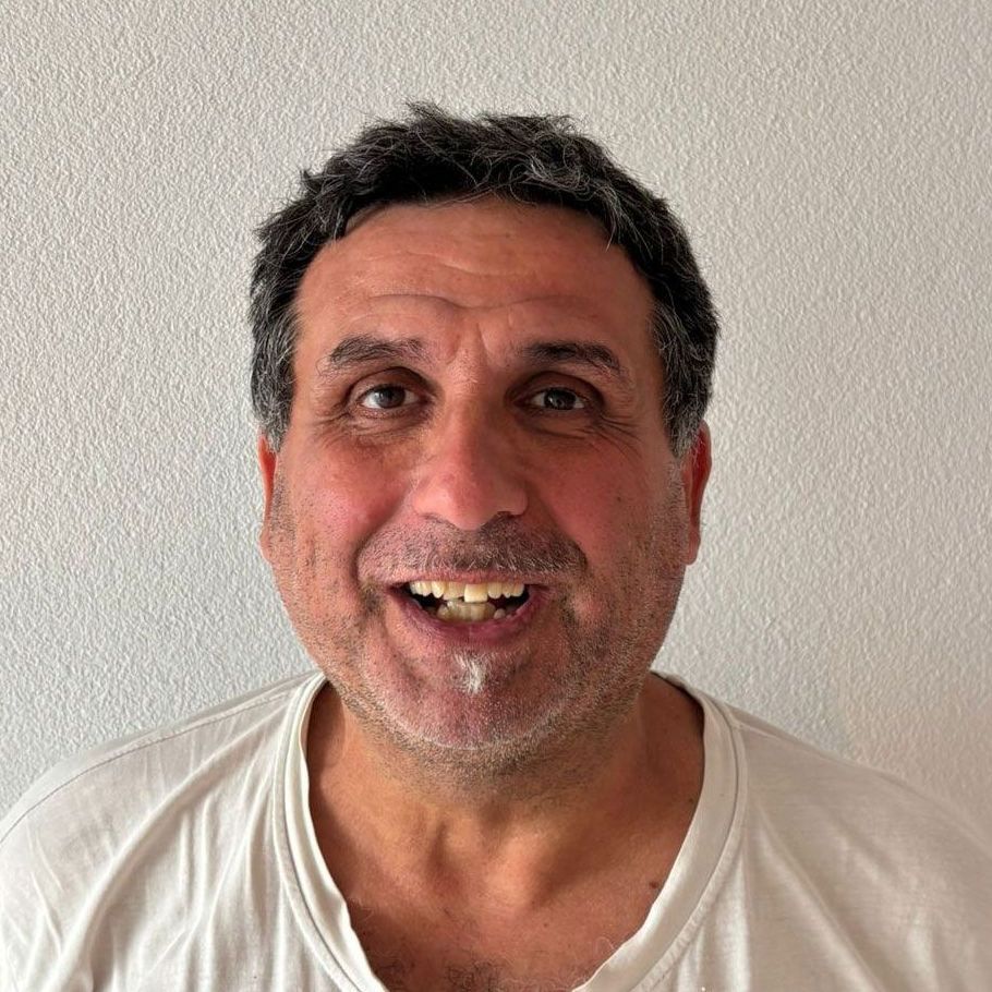 Ein Mann in einem weißen Hemd lächelt mit offenem Mund.