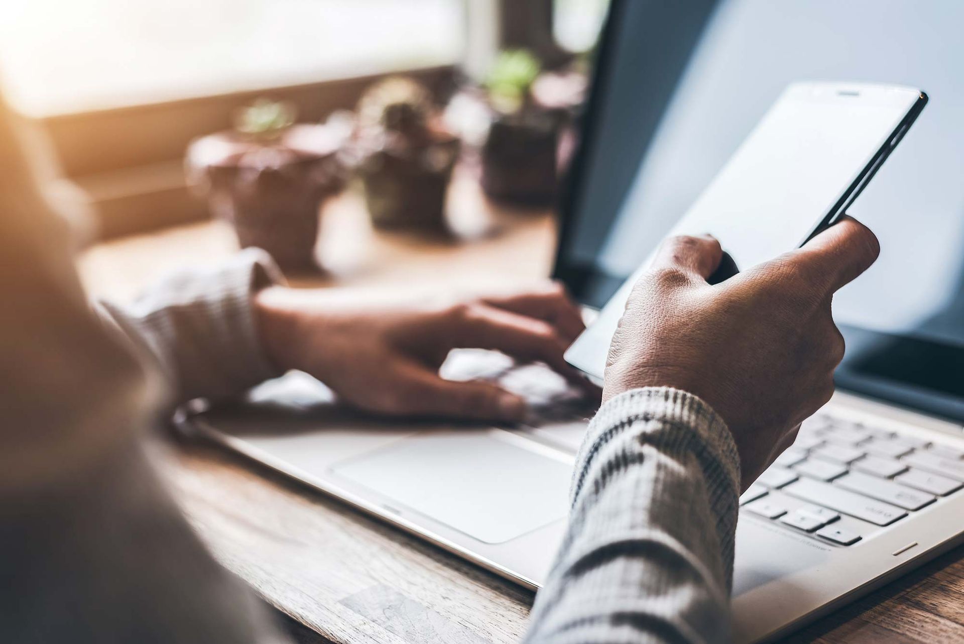 Eine Person verwendet gleichzeitig einen Laptop und ein Mobiltelefon.