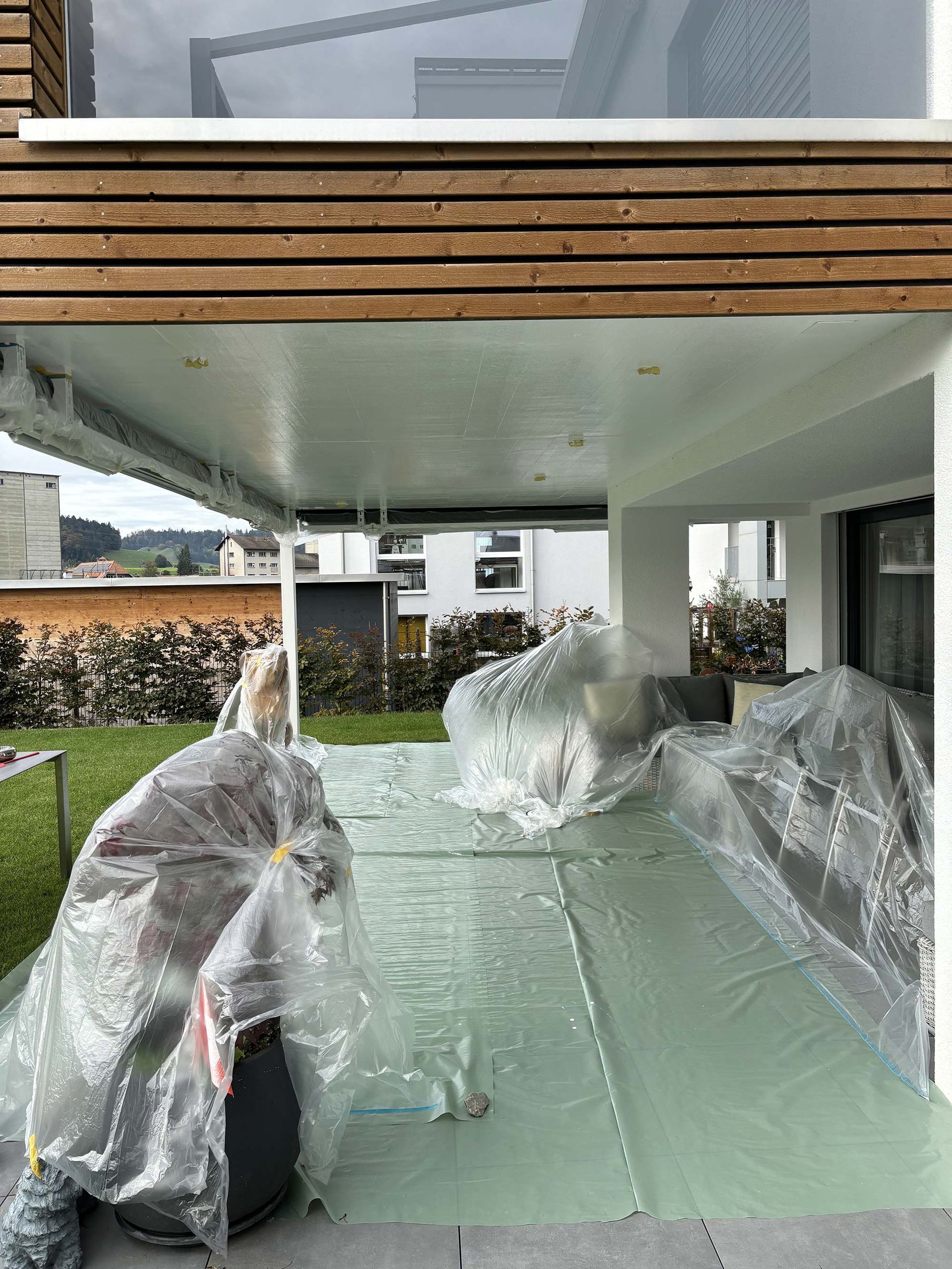 Eine Person steht vor einem mit Plastik bedeckten Haus.