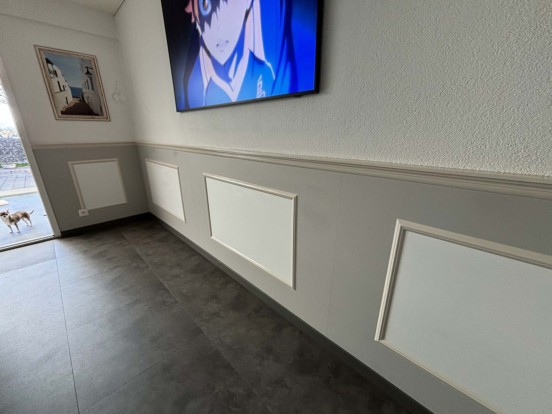 Ein Zimmer mit einem Fernseher und einem Gemälde an der Wand.