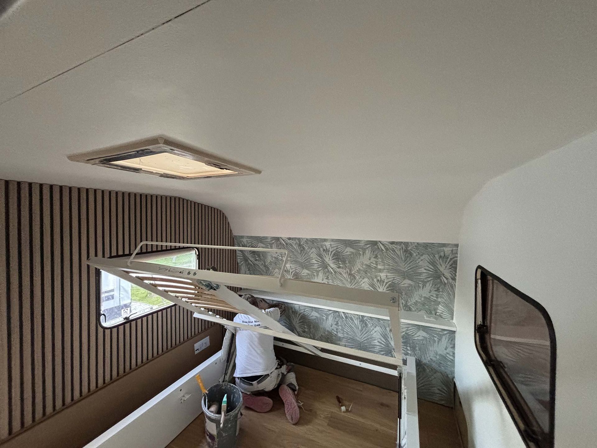 Ein Mann arbeitet an der Decke eines Wohnmobils.