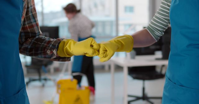 Reinigungsmittel in einem grünen Eimer mit Mopp, Handschuhen, Sprühflaschen und Tüchern auf einem Holzboden