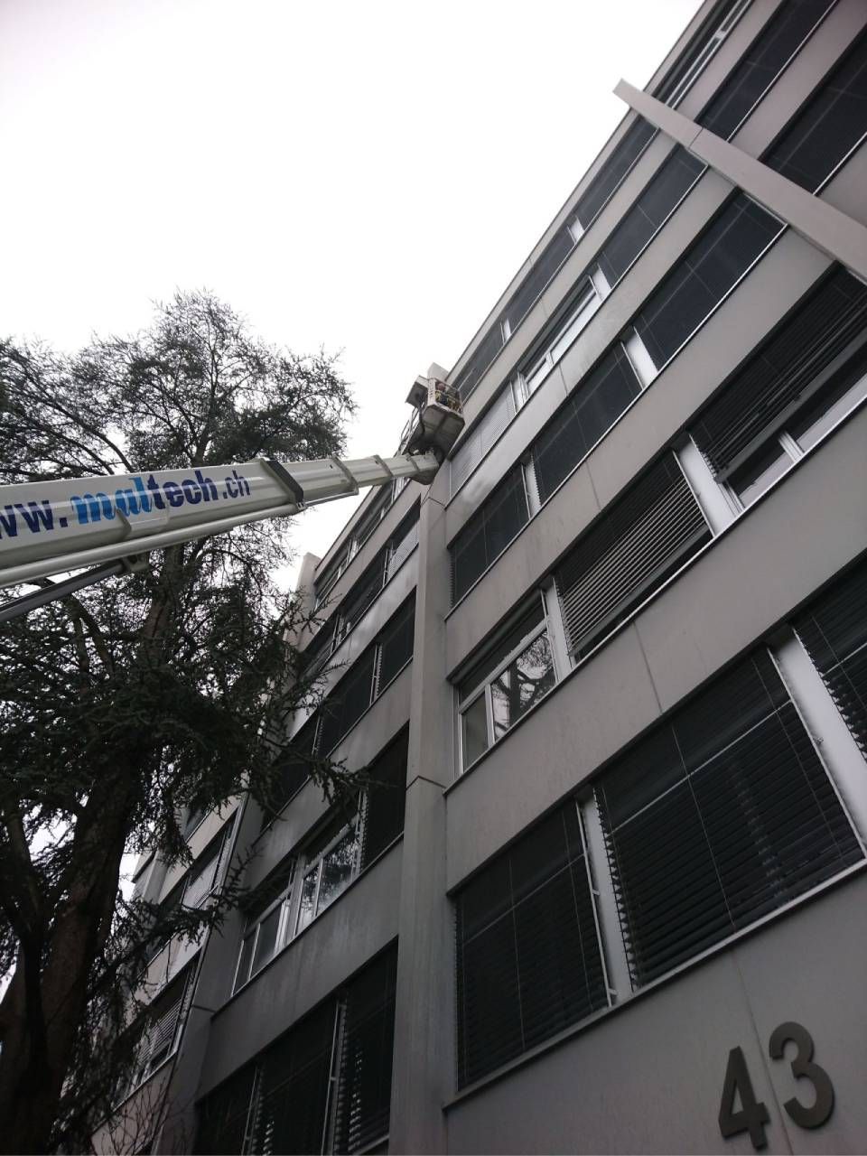 Eine Person, die blaue Handschuhe trägt, putzt ein Fenster mit einem Abzieher.