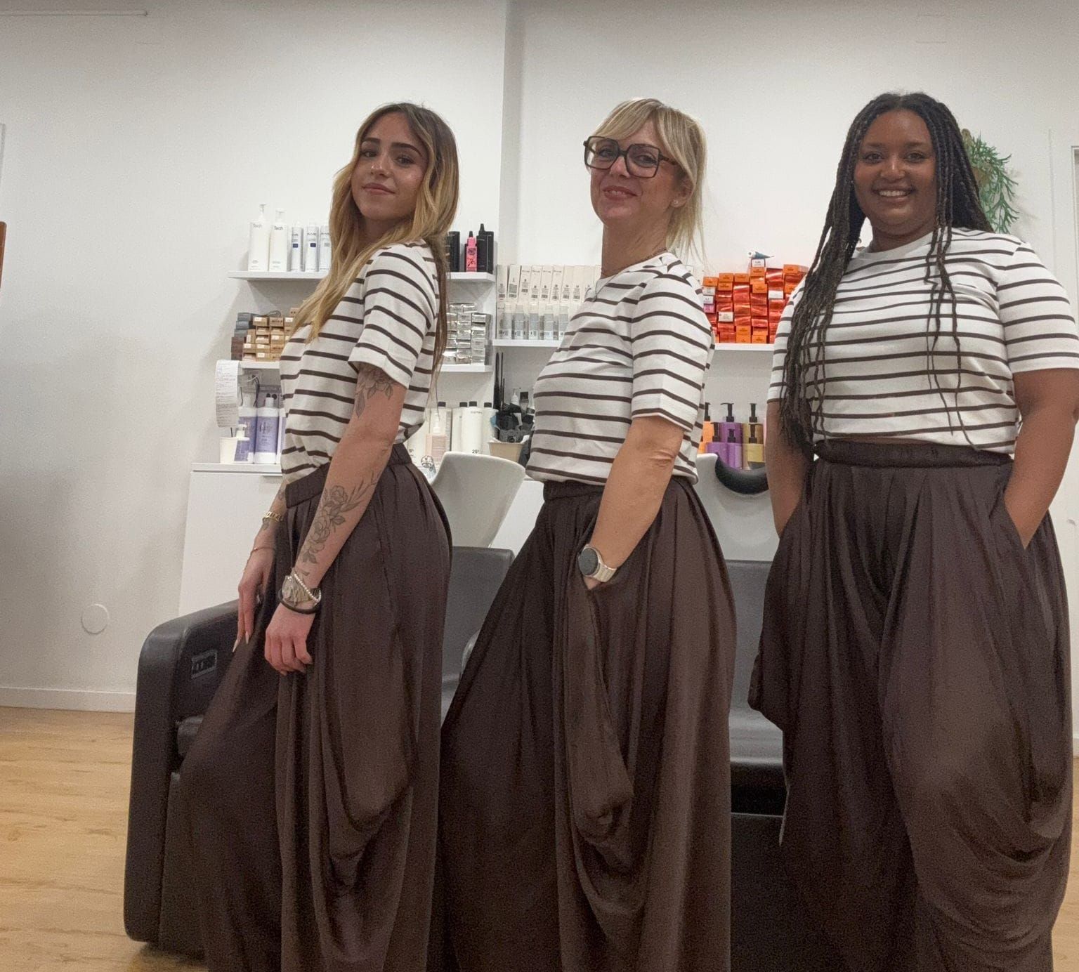 Una persona peinándose el cabello en un moño alto, sujetando con las manos una pequeña sección separada de cabello rizado y oscuro.