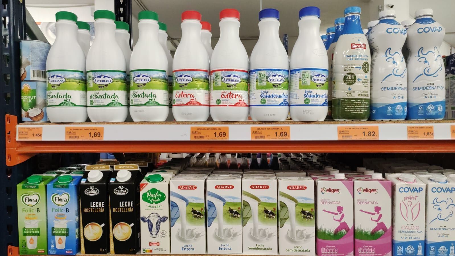 Un estante en una tienda lleno de botellas y cartones de leche.
