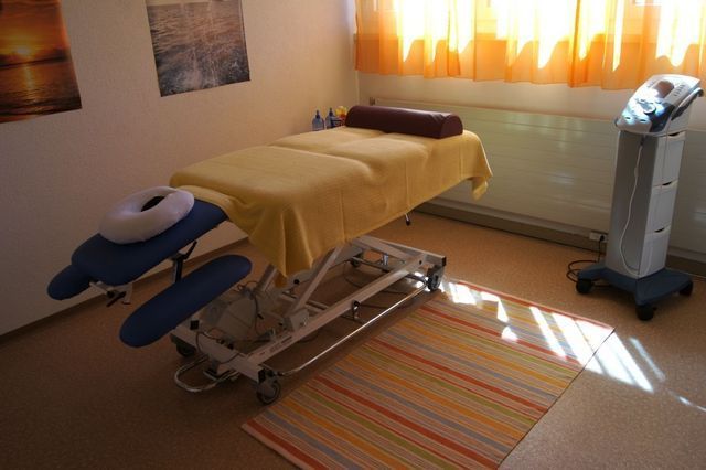 In einem Raum neben einem Fenster steht ein Massagetisch.