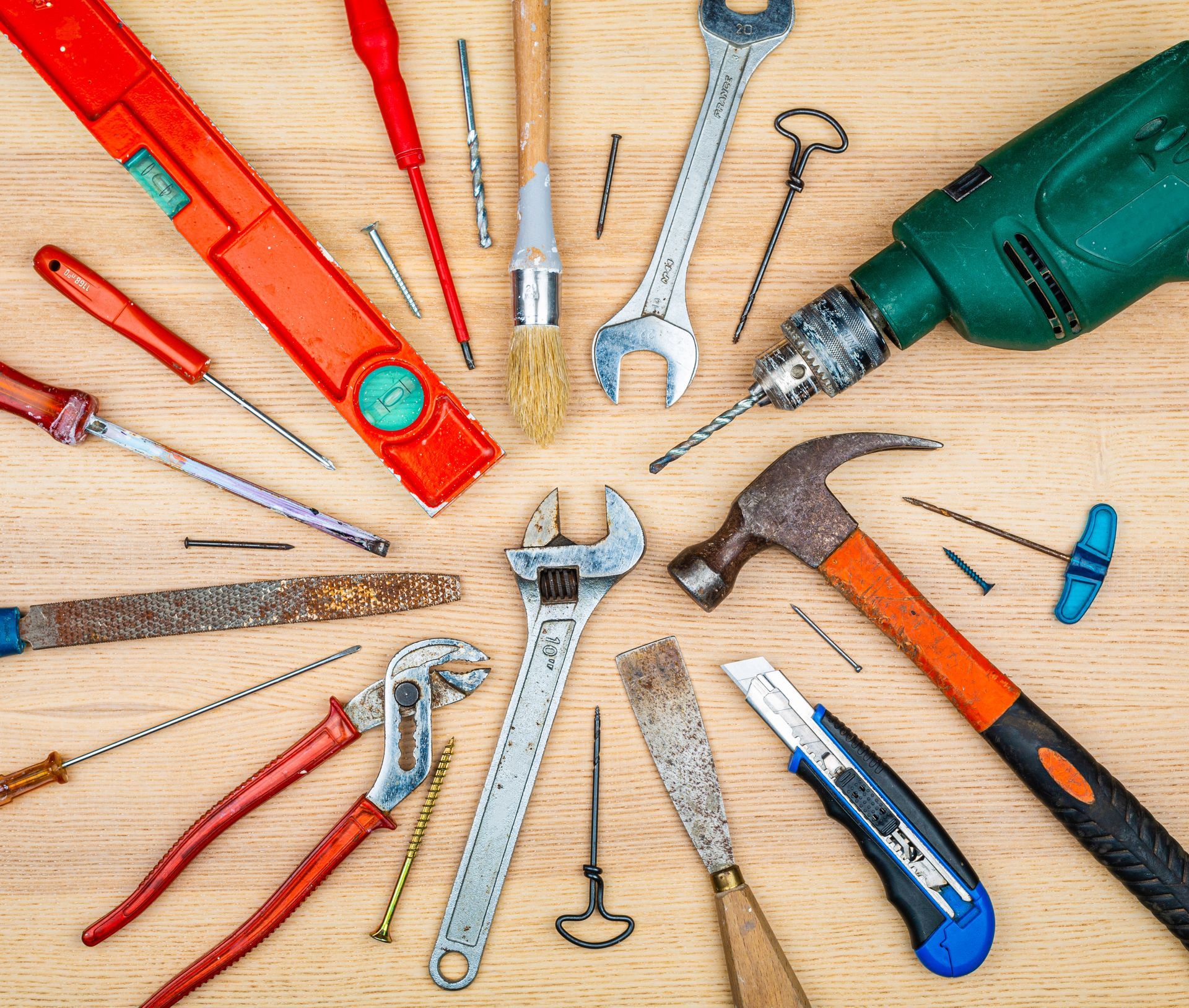 Assortiment d'outils dont un niveau, un tournevis, une clé, une perceuse et un marteau.