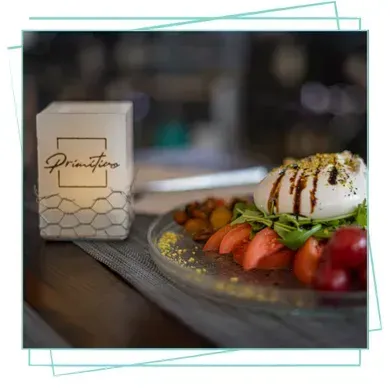 Un plato de burrata con tomates y glaseado balsámico junto a una linterna 