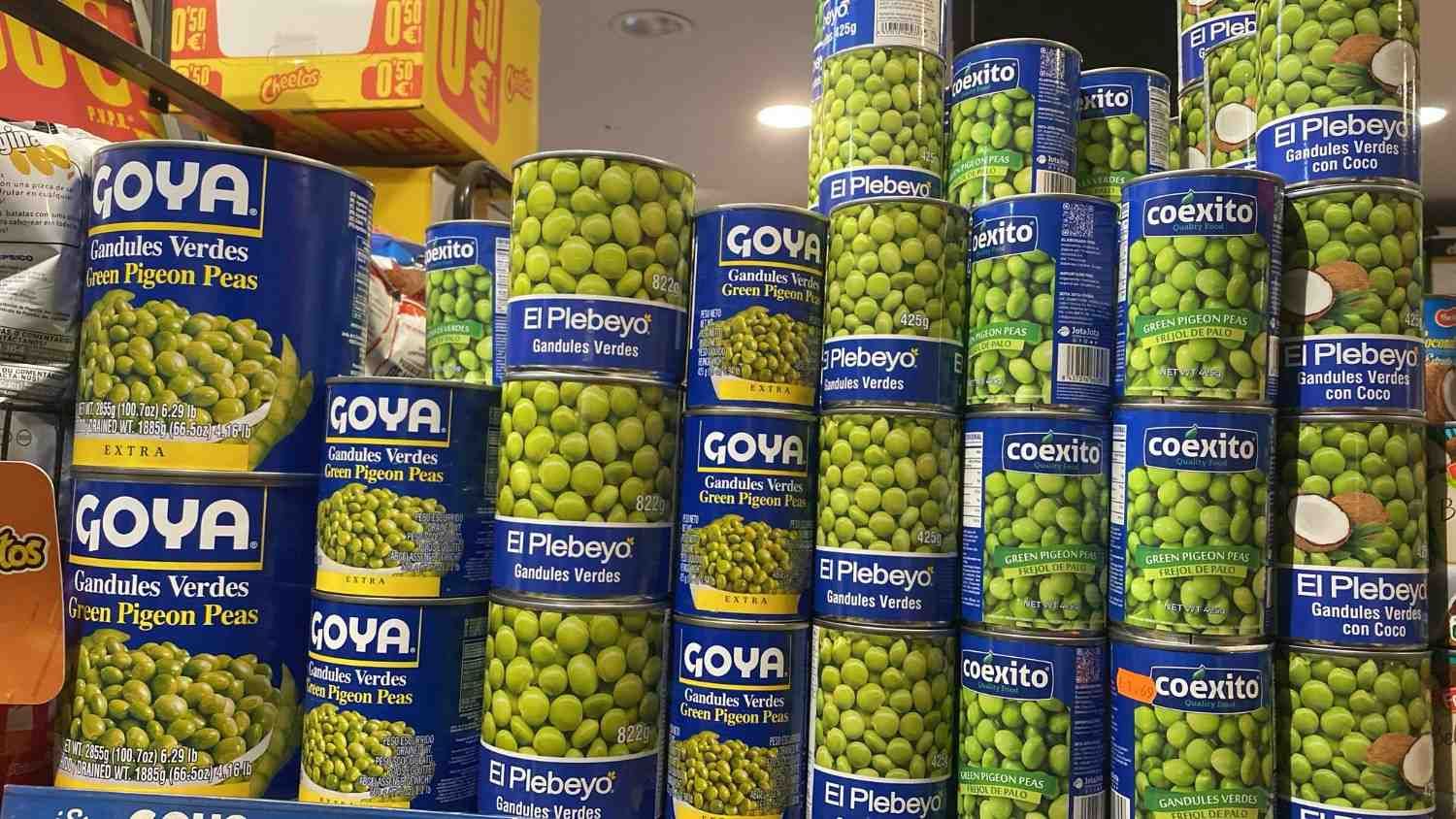Estantes repletos de guisantes verdes enlatados GOYA de color azul en una tienda de comestibles.